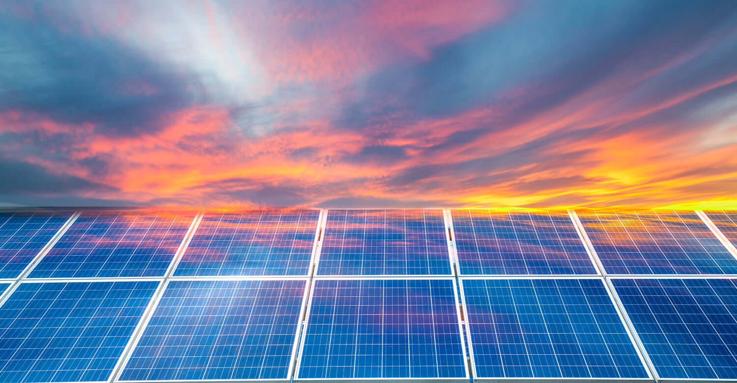 Solar panels under a colorful sky at sunset, illustrating how to be a solar advocate.
