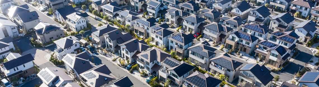 Aerial view of houses with solar panels, illustrating Grid-tied solar vs off-grid: Which is the better investment.
