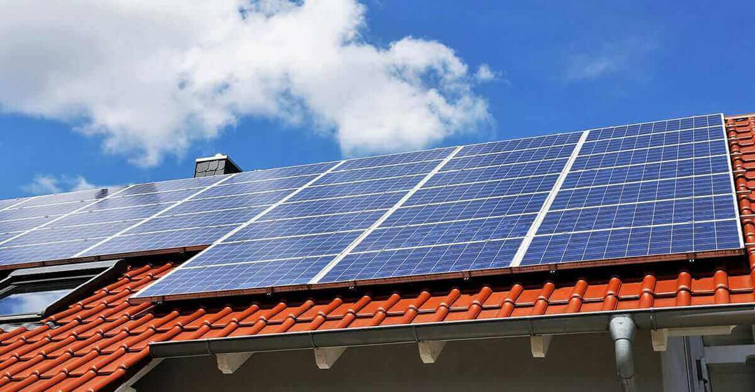 How long do solar panels last on a roof with solar panels and clear blue sky in the background.