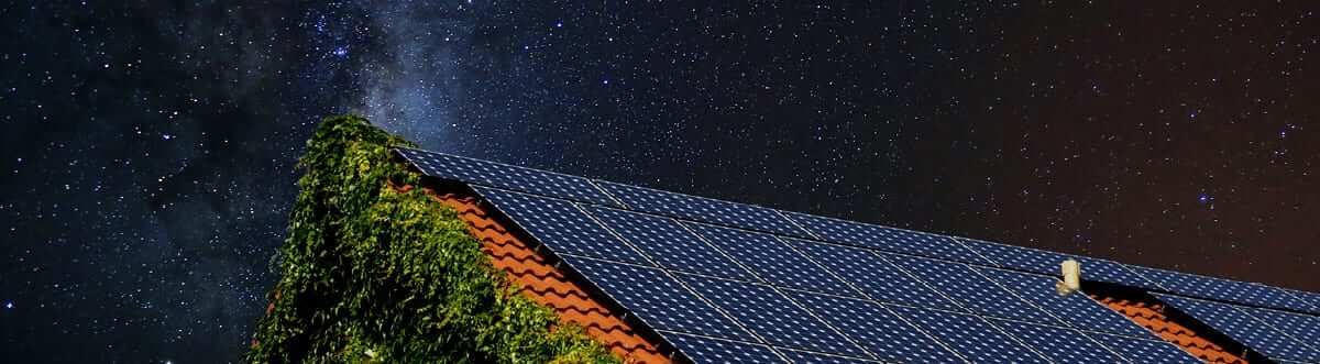 Solar panels on a roof under the night sky, exploring if solar keeps the power on during a power outage.